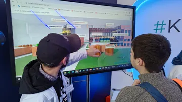 Osoba w białym fartuchu pokazuje na ekranie dotykowym model bloku elektrowni jądrowej typu PWR