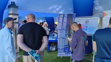 Zwiedzający przy planszach o energetyce jądrowej w namiocie wystawowym