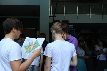 Uczniowie z ulotkami przy stoisku Fundacji w hali laboratoryjnej AGH