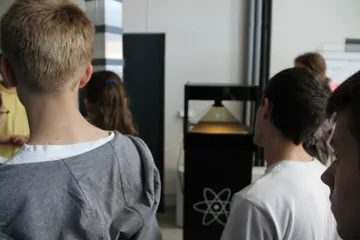 Zwiedzający przy gablocie z symbolem atomu