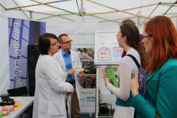 Rozmowa przy stoisku; zwiedzające trzymają materiały Fundacji