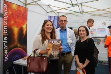Zwiedzający z czasopismem „Forum Atomowe” pozują z osobą z Fundacji