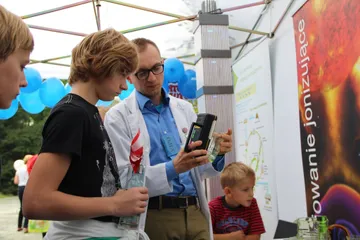 Osoba w białym fartuchu pokazuje chłopcu miernik promieniowania