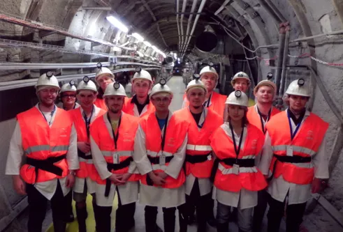 Wolontariusze w kaskach i pomarańczowych kamizelkach w podziemnym tunelu laboratorium