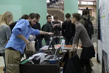 Pokaz z przyrządami pomiarowymi przy stole; wokół studenci