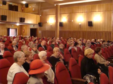 Słuchacze w czerwonych fotelach podczas wykładu