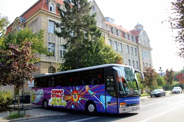 Atomowy Autobus na ulicy przed zabytkowym budynkiem szkoły