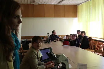 Uczestnicy zajęć przy dużym stole z mikroskopem i laptopem