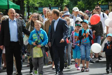 Goście pikniku z dziećmi idą alejką na terenie Kancelarii Prezesa Rady Ministrów