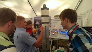 Dziecko uruchamia makietę elektrowni jądrowej przy osobie z Fundacji