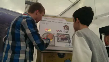 Osoba z Fundacji objaśnia makietę elektrowni chłopcu