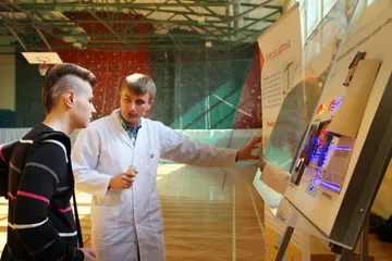 Osoba w białym fartuchu objaśnia uczniowi podświetlany model elektrowni jądrowej