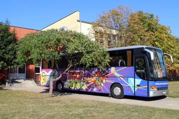 Atomowy Autobus zaparkowany przy szkole wśród drzew