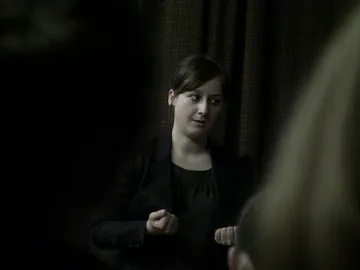 Osoba prowadząca zajęcia mówi do uczniów w zaciemnionej sali