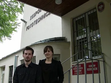 Dwie osoby prowadzące zajęcia przed wejściem do budynku Zespołu Szkół Fototechnicznych
