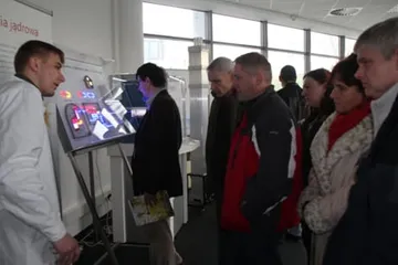 Zwiedzający przy interaktywnym ekranie; obok osoba w białym fartuchu