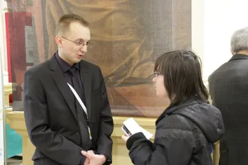Osoba z identyfikatorem rozmawia z osobą trzymającą dyktafon