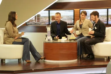 Rozmowa w studiu telewizyjnym przy stoliku z eksponatami: osoba prowadząca i trzy osoby z Fundacji