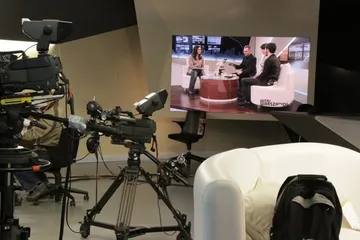 Kamera telewizyjna w studiu; na monitorze rozmowa z gośćmi