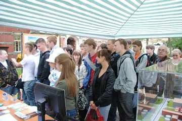 Tłum młodzieży wokół makiety elektrowni jądrowej pod pasiastym namiotem