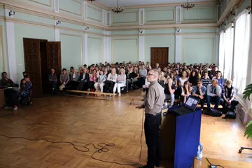 Prelegent przy mównicy przed pełną salą uczniów
