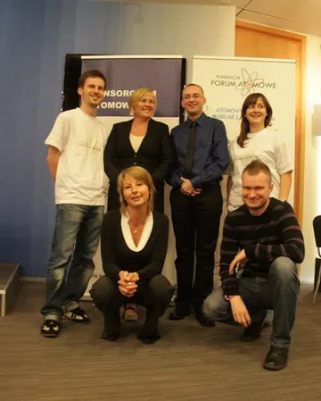 Grupa sześciu osób pozuje przy roll-upach Konsorcjum Atomowego i Fundacji