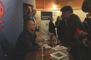 Rozmowy przy stole prezydialnym po konferencji; w tle roll-up Konsorcjum Atomowego