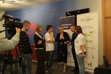 Rozmowy uczestników przed kamerą na tle roll-upów Konsorcjum Atomowego i Fundacji