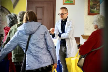 Mieszkańcy przy stoiskach; w tle osoba w białym fartuchu