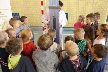 Uczniowie przy makiecie kasety paliwowej słuchają osoby w białym fartuchu
