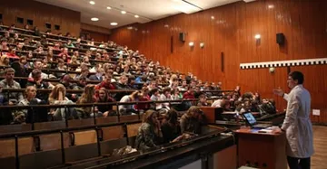 Pełna sala wykładowa podczas seminarium; przy katedrze osoba w białym fartuchu