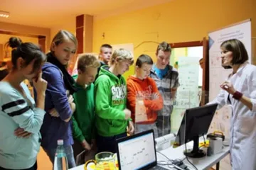 Uczniowie przy stoisku z laptopem i planszami