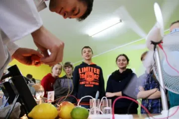 Uczniowie obserwują doświadczenie z cytrynami i modelem turbiny wiatrowej