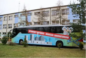 Żółty Atomowy Autobus przed budynkiem szkoły