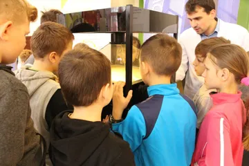 Dzieci zaglądają do gabloty z hologramem