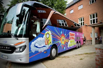 Fioletowy Atomowy Autobus przed ceglanym budynkiem szkoły