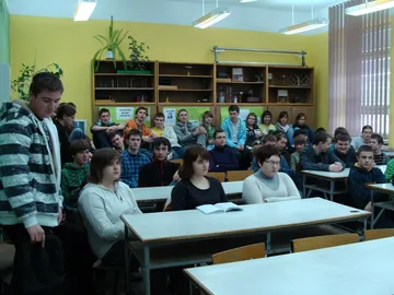 Uczniowie liceum w pracowni fizycznej, z boku stoi uczeń w pasiastej bluzie