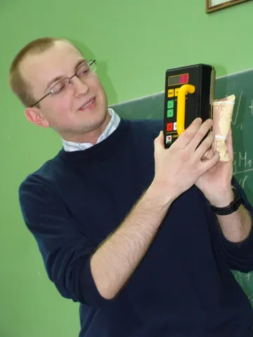 Osoba prowadząca zajęcia pokazuje miernik promieniowania
