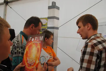 Zwiedzający z czasopismem „Forum Atomowe” rozmawiają z osobą z Fundacji