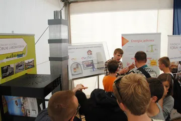 Tłum zwiedzających przy stoisku z makietą kasety paliwowej w namiocie