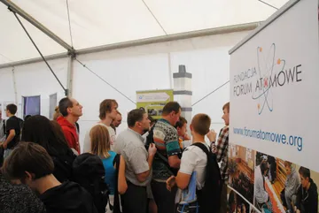Zwiedzający w namiocie przy roll-upie Fundacji FORUM ATOMOWE