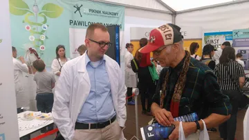 Osoba w białym fartuchu na stoisku Fundacji w Pawilonie Francuskim 20. Pikniku Naukowego