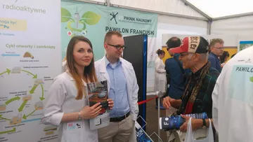 Dwie osoby z Fundacji z czasopismem „Forum Atomowe” przy planszy o cyklu paliwowym