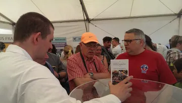 Rozmowa ze zwiedzającymi; jeden z nich trzyma broszurę