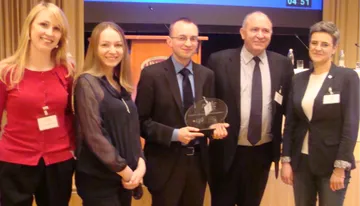 Pięć osób pozuje ze szklaną statuetką nagrody