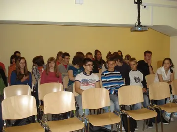Uczniowie w sali wykładowej; pierwsze rzędy krzeseł są puste