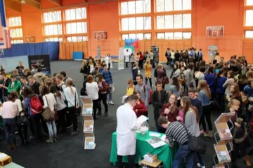 Widok z góry na salę gimnastyczną pełną uczniów przy stoiskach