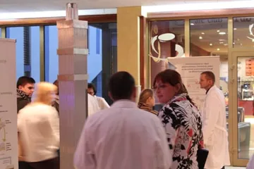 Zwiedzający przy stoiskach z planszami w holu uczelni