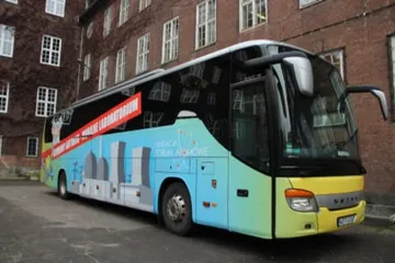 Żółty Atomowy Autobus przed ceglanym budynkiem szkoły