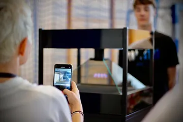 Uczeń fotografuje telefonem gablotę z hologramem